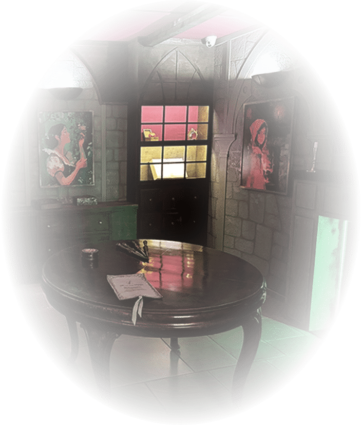 escape-game-Il-était-une-fois-photo-interne-2 Une table est au centre de la salle d'escape game il était une fois. Des tableaux sont accrochés au mur.